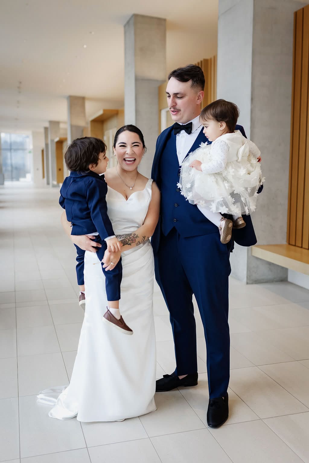 Bride and groom laughing while holding their two little ones